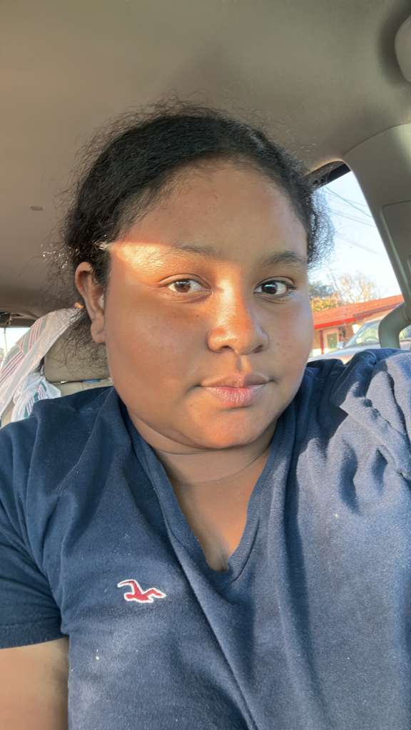 Sunlight hits the face of a person wearing a navy blue shirt in a car.